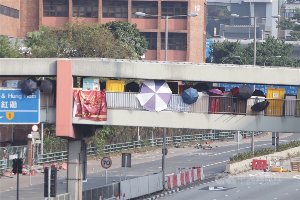 示威者用雨傘遮擋自己,在橋上向海底隧道路面投下雜物。中央社記者張謙香港攝 108年11月14日
