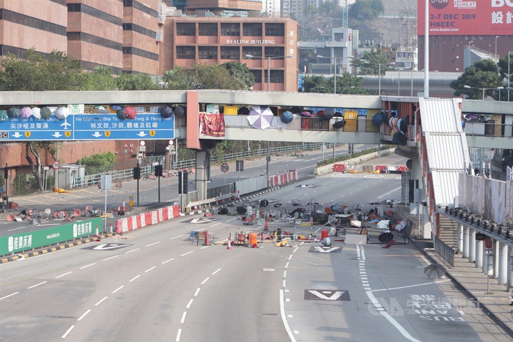 示威者從橋上向海底隧道路面投下雜物,令道路阻塞。圖為示威者站在連接理工大學的橋上,用雨傘遮擋自己。中央社記者張謙香港攝 108年11月14日