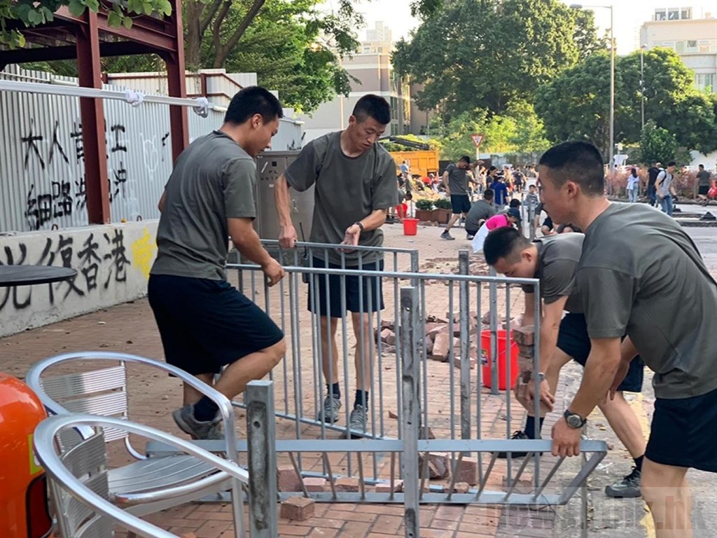 一批解放軍駐香港部隊官兵16日下午現身九龍塘浸會大學聯福道周邊馬路,沿路清理「反送中」示威者設下的磚頭、鐵柵欄等路障。(圖取自香港電台網頁news.rthk.hk)