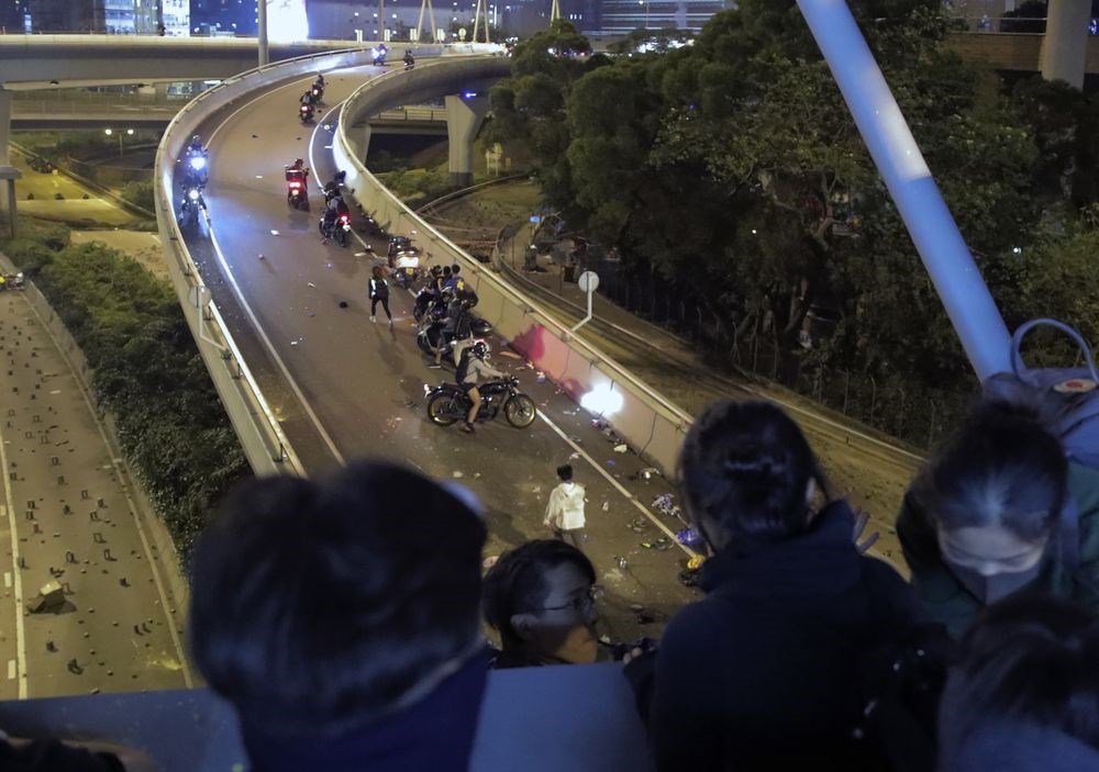 香港理工大學示威者持續被困,有上百人18日晚間改用吊繩,試圖跳下馬路逃出校園,似有少數人被前往聲援的電動機車接走。(美聯社)