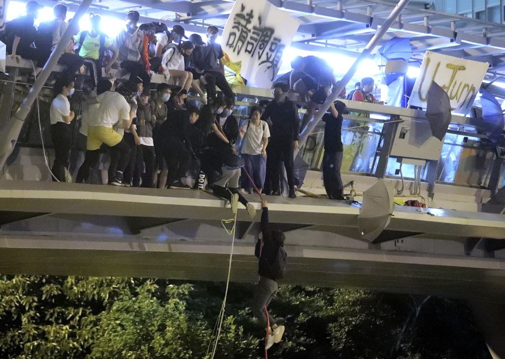 香港理工大學示威者持續被困,上百人18日晚間改用吊繩,試圖跳下馬路逃出校園,似有少數人被前往聲援的電動機車接走。(美聯社)