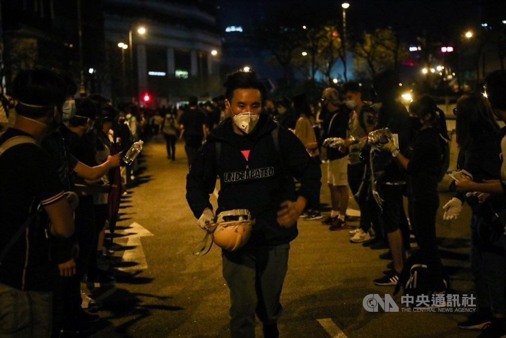 香港理工大學內的反送中示威者持續被港警包圍,校外的示威民眾18日深夜在尖東一帶與警方對峙,將頭盔從後方運往前線。中央社記者吳家昇攝 108年11月19日