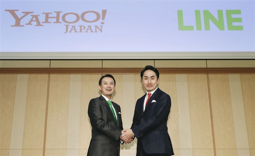 雅虎日本母公司ZHD與LINE 18日宣布將進行合併,成日本境內最大IT企業。圖為ZHD社長川邊健太郎(左)與LINE社長出澤剛在記者會上握手。(共同社提供)