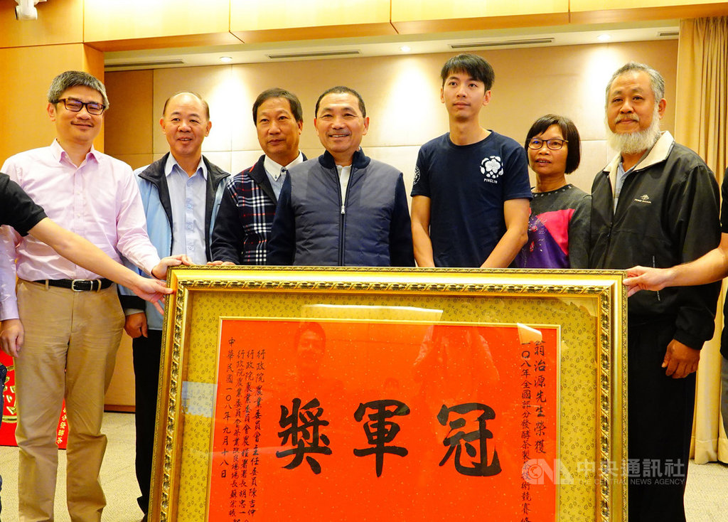 77年次的翁治源(右3)是電機碩士,5年前決定返家種茶,今年奪下「全國部分發酵茶製茶技術競賽」冠軍,他20日將冠軍獎牌獻給新北市長侯友宜(右4),並獲贈匾肯定。(農業局提供)中央社記者王鴻國傳真 108年11月20日