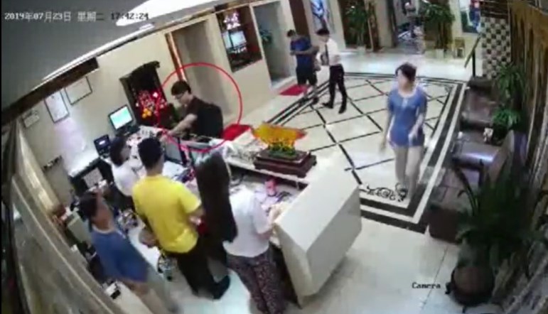 中國官方21日以深圳警方接受媒體採訪的名義公布一段影片,聲稱是英國駐香港總領事館雇員鄭文傑(紅圈標註者)嫖娼及事後接受偵訊的畫面。(圖取自人民日報微博網頁weibo.com)