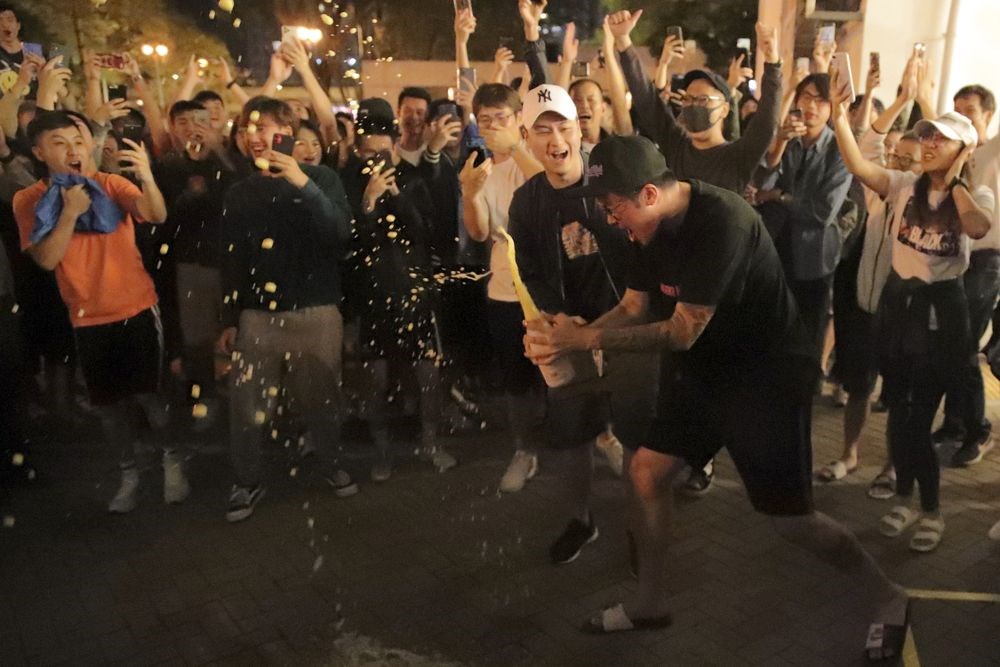 香港泛民主派在地方區議會選舉中大獲全勝,親中建制派則大敗。圖為建制派候選人何君堯確定落選後,泛民派支持者在街頭開香檳慶祝。(美聯社)