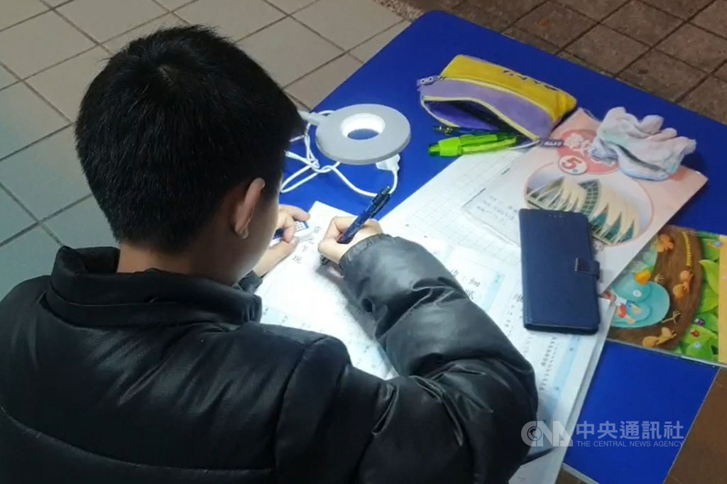 陳姓單親母親一度窮到只剩新台幣7元,近期才順利在宜蘭賣烤地瓜謀生,她就讀國小5年級的兒子(圖)放學後都在騎樓燈光下「借光夜讀」伴母。經報導後,29日各界愛心不斷湧入,還有人送上檯燈,讓男童唸書時光線更好。中央社記者沈如峰宜蘭縣攝 108年11月29日
