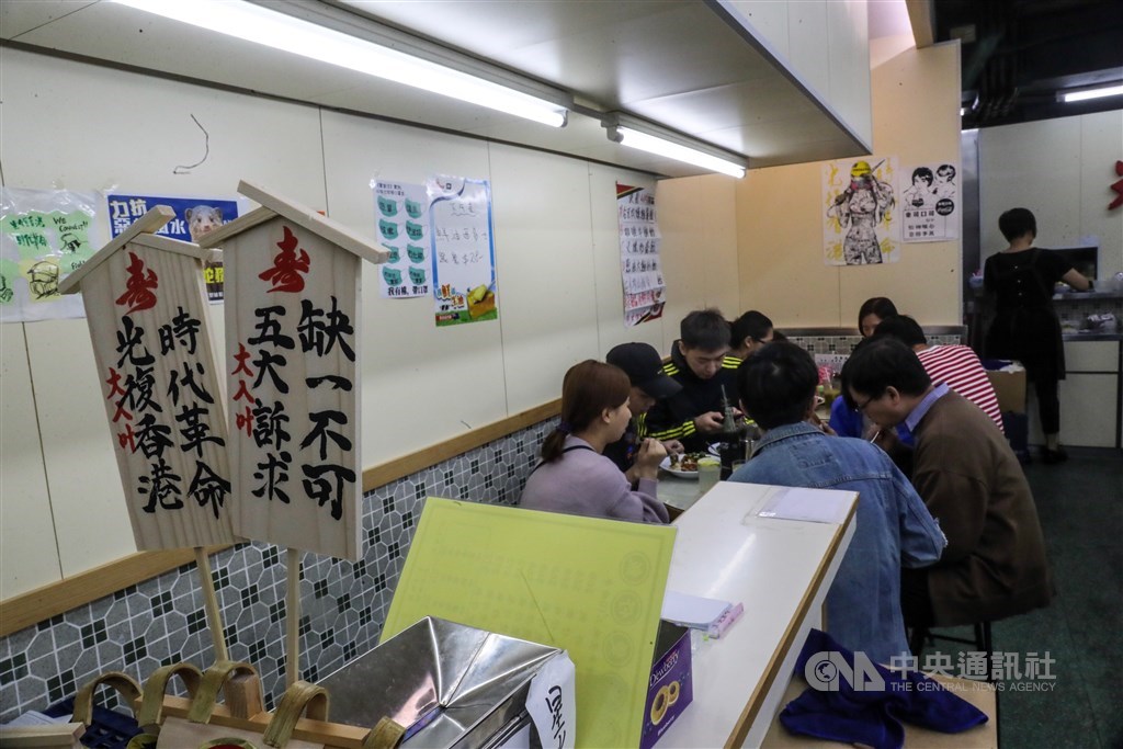 光榮冰室荃灣店大方展示寫著「五大訴求缺一不可」「光復香港 時代革命」的立牌。用餐時間店裡經常滿座,門外還有人排隊。中央社記者吳家昇攝 108年11月21日