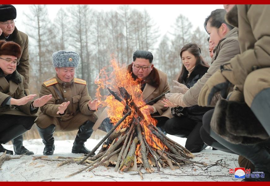 北韓自訂與美國對話期限將近,北韓領導人金正恩(中)登白頭山。圖為金正恩夫婦和眾人圍著篝火暖手的照片。(圖取自北韓中央通信社網頁kcna.kp)