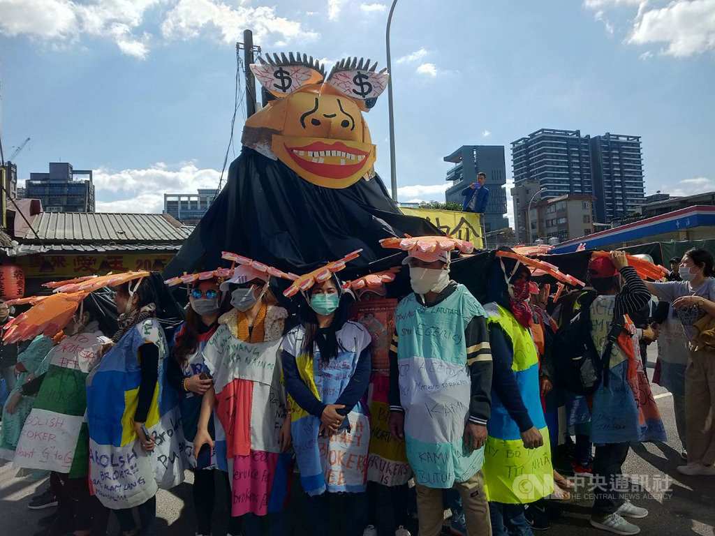 台灣移工聯盟8日舉辦移工大遊行,訴求廢除私人仲介制度、要求政府對政府直接聘僱,移工自製象徵私人仲介的大型人偶,並由大型人偶延伸出許多手壓在移工頭頂,象徵移工受到壓迫。中央社記者張雄風攝 108年12月8日