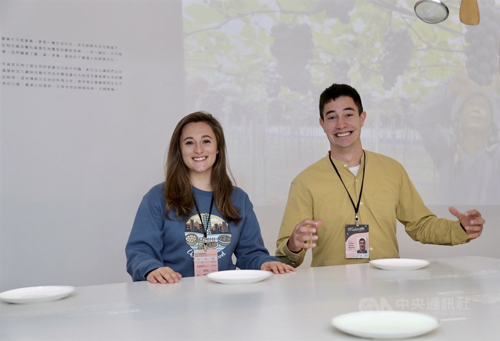 來自加拿大的美食網紅馬丁(Lukas Dean Martin)(右)和戴維森(Sabrina Frances Davidson)(左),參加「來去總統府住一晚」體驗活動,12日參觀總統府。戴維森特別穿上Chopstick Travel新推出的限量版長袖T恤,上面印有台灣的4大代表性小吃:小籠包、奶茶、臭豆腐和牛肉麵,背景則是台北101大樓。中央社記者張皓安攝 108年12月12日