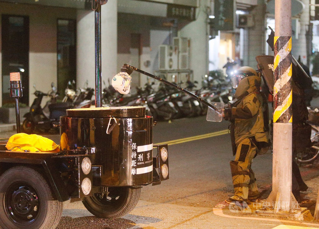 警方追查涉嫌在國民黨台南市後壁區黨部大門旁放置不明物體的男子,13日循線在高雄市苓雅區永樂街一棟大樓包抄攻堅,雙方對峙,犯嫌一度丟出一罐疑裝有不明液體的寶特瓶,防爆小組全副武裝,夾取寶特瓶。中央社記者董俊志攝 108年12月13日