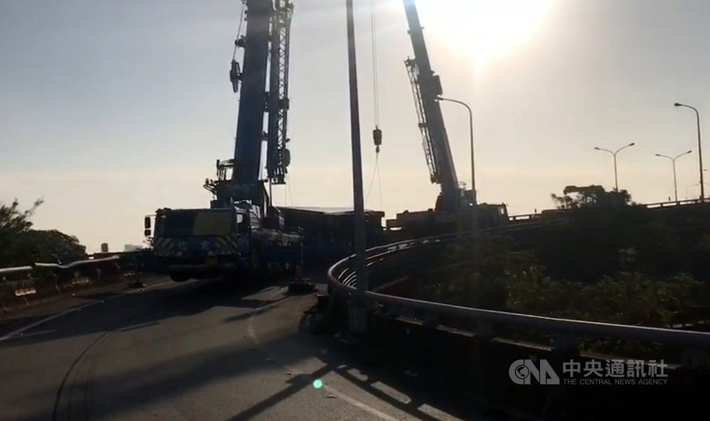 一輛大貨車13日行經國道1號高速公路平鎮系統交流道時,疑似轉彎過快,在匝道彎處側翻,撞擊外側路肩及護欄,警方動用大型拖吊車處理。(國道公路警察局提供)中央社記者邱俊欽桃園傳真 108年12月13日