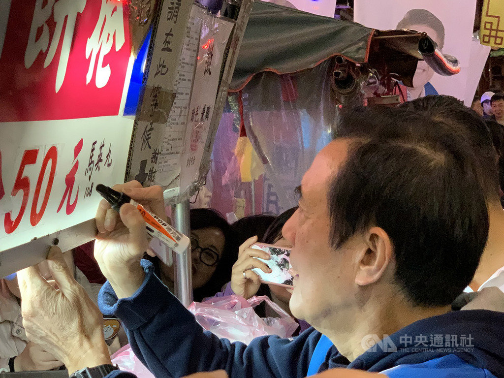 前總統馬英九(前)14日陪同國民黨籍新北市立委參選人陳明義至新莊慈祐宮參香,隨後並在廟前知名潤餅攤位招牌上簽名。中央社記者葉臻攝 108年12月14日