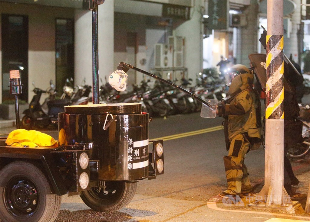 警方追查涉嫌在國民黨台南市後壁區黨部大門旁放置不明物體的男子,13日循線在高雄市苓雅區永樂街一棟大樓包抄攻堅,雙方對峙,犯嫌一度丟出一罐疑裝有不明液體的寶特瓶,防爆小組全副武裝,夾取寶特瓶。中央社記者董俊志攝 108年12月13日