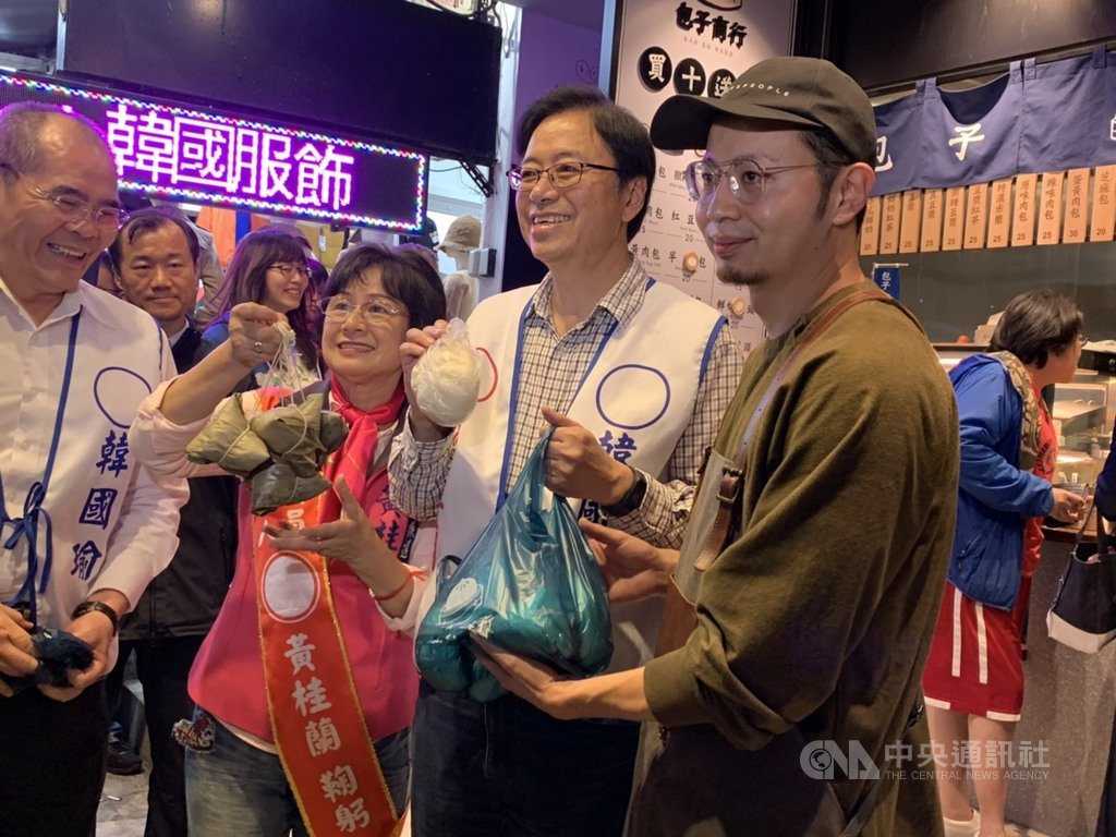 國民黨副總統候選人張善政(前右2)15日晚間到新北市蘆洲廟口夜市,陪同黨籍立委參選人黃桂蘭(前左2)掃街拜票,有店家致贈象徵「包中」的包子和粽子。中央社記者葉臻攝 108年12月15日
