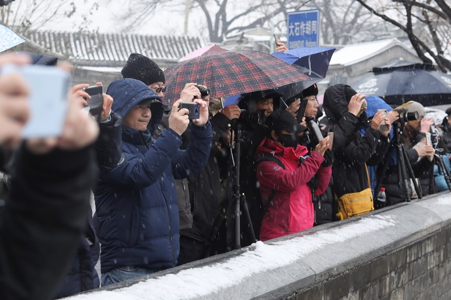 16日一早許多北京居民一出門就被白雪包圍,不少地方銀裝素裹、雪花紛飛,讓人興奮不已,不顧寒冷站在街頭拍照並立即分享在社群媒體。(中新社提供)