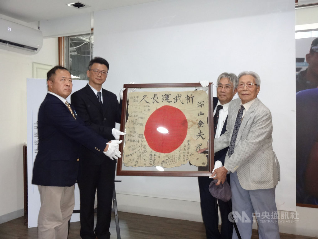 流落海外70多年、寫著祝福的一面日章旗捐贈儀式,由高雄市關懷台籍老兵文化協會理事長吳祝榮(右2)主持,並代表協會從日籍友人永山英樹(左)手中接下日章旗。中央社記者陳朝福攝 108年12月18日