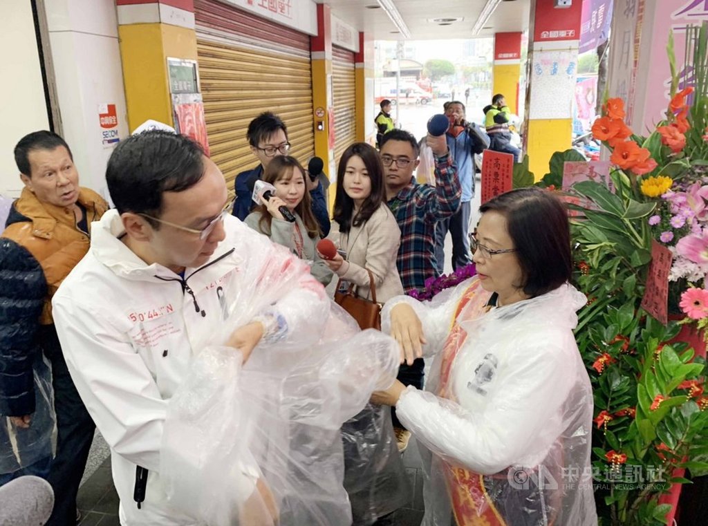 前新北市長朱立倫(前左)30日陪同無黨籍立委參選人李翁月娥(前右)車隊掃街,下著大雨,李翁月娥協助朱立倫穿上輕便雨衣。中央社記者葉臻攝 108年12月30日