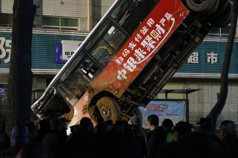 中國青海省西寧市一處公車站昨天下午忽然發生路面塌陷,導致一輛正在進站的公車車頭朝下墜入坑中,目前公車已被吊掛出坑。(中新社提供)
