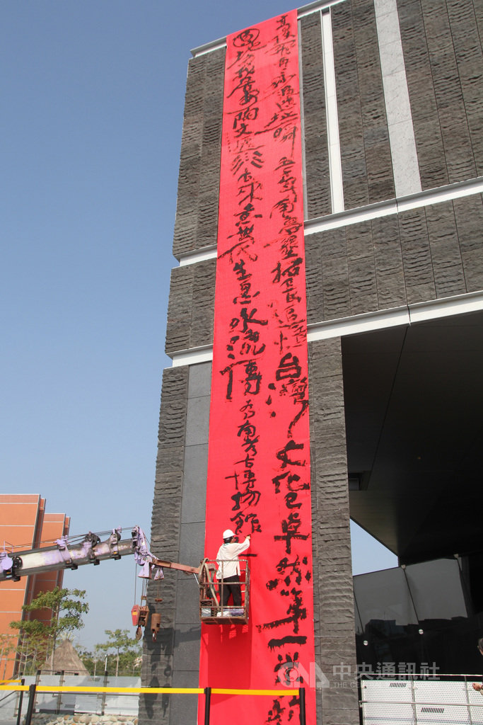 國立台灣史前文化博物館南科考古館19日邀請意象書法家陳世憲進行創作,在館外牆的大型紅色絹布上書寫詩句。中央社記者楊思瑞攝 109年1月19日