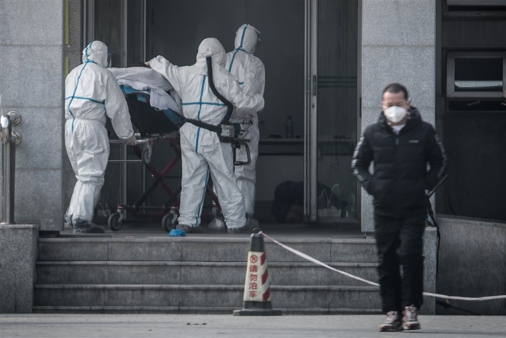 武漢市肺炎疫情防控指揮部已發布通告表示,自23日上午10時起,全市公車、地鐵、輪渡、長途客運暫停運營。圖為醫護人員將患者送入武漢金銀潭醫院。(法新社提供)
