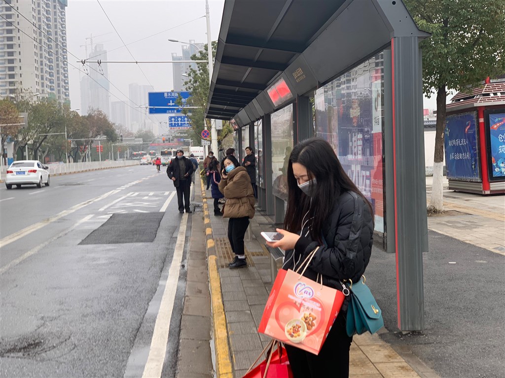中國武漢大學人民醫院發布報告指出,有些武漢肺炎的患者一開始並沒有典型的發燒、咳嗽、乏力症狀,增加了診斷難度和傳染機會。圖為23日武漢市民眾戴口罩等候公車。(中新社提供)
