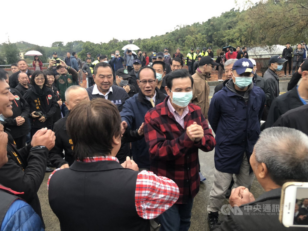 前總統馬英九(前中)26日年初二前往苗栗縣通霄鎮馬家庄祭祖,雖然下著雨,仍吸引近百名鄉親排隊領取福卡;因應武漢肺炎疫情,馬英九全程戴口罩、拱手不握手向民眾拜年。中央社記者管瑞平攝 109年1月26日