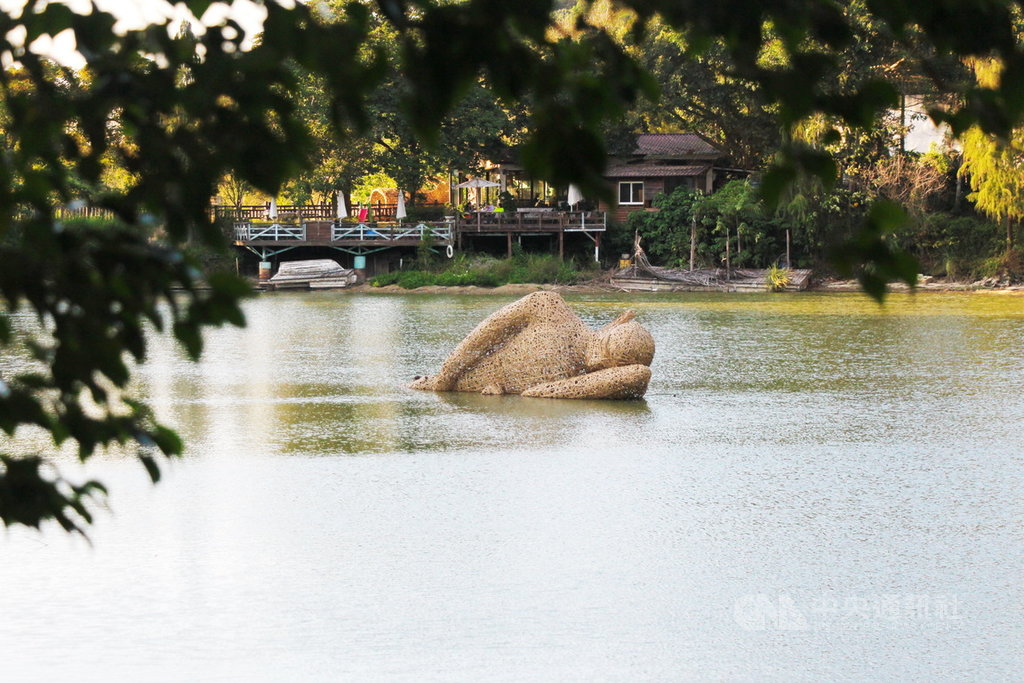 新竹縣政府邀6名印尼藝術家在峨眉鄉十二寮大埤湖中打造地景藝術,其中竹編打造半躺半臥人像「懶散時光」寓意是提醒觀看者善待自然。中央社記者郭宣彣攝 109年1月28日