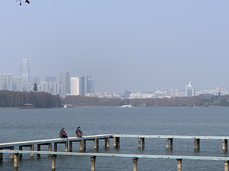 2020中國經濟重大目標是年底GDP要比2010年成長一倍,在武漢肺炎衝擊下,想完成這項目標突然懸念重重。圖為29日武漢封城第7天,戴著口罩的民眾在東湖棧橋垂釣。(中新社提供)