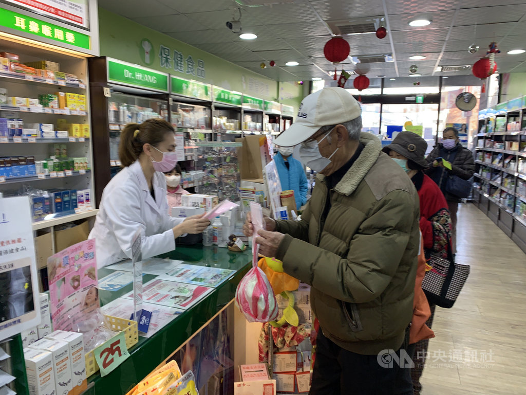 口罩實名制6日上路,藥師向民眾收健保卡過卡並收取現金後給予口罩,過程十分快速。中央社記者葉臻攝 109年2月6日