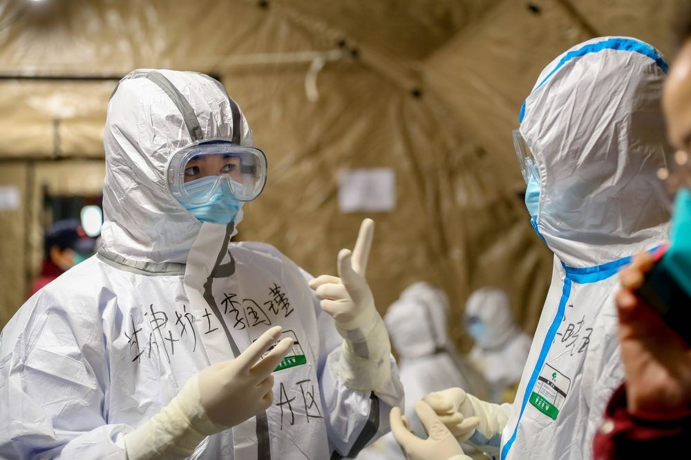 湖北省武漢肺炎確診病例12日暴增一萬多人受矚。圖為武漢方艙醫院醫療人員用手勢溝通。(中新社提供)
