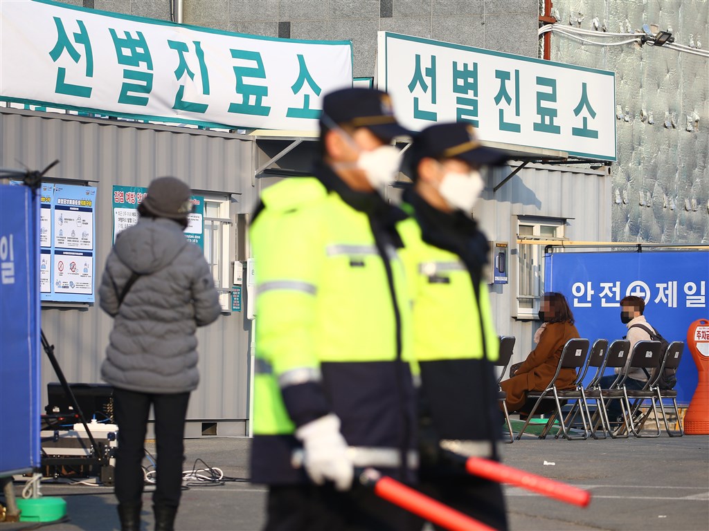 南韓武漢肺炎疫情擴散,19日及20日先後出現20例及31例確診感染病例,其中至少37例都與日前確診的61歲大邱婦人有關。圖為大邱一間醫療中心前,巡邏警察戴著口罩。(韓聯社提供)