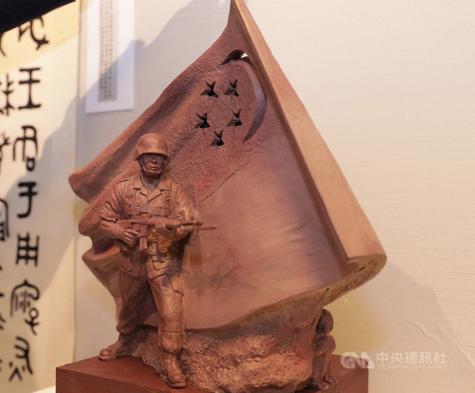 新加坡德光島軍人持槍站在飄揚國旗下蓄勢待發的巨型雕塑,是台灣雕塑家陳連山作品,圖為陳連山展出這座原創版「國民服役」雕塑模型。中央社記者黃自強新加坡攝 109年2月21日