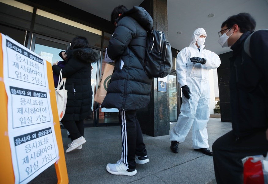 韓國政府23日將武漢疫情預警上調至最高等級「嚴重」,並強化應對措施。圖為韓國會計師考試試場檢疫人員引導考生進入考場。(韓聯社提供)