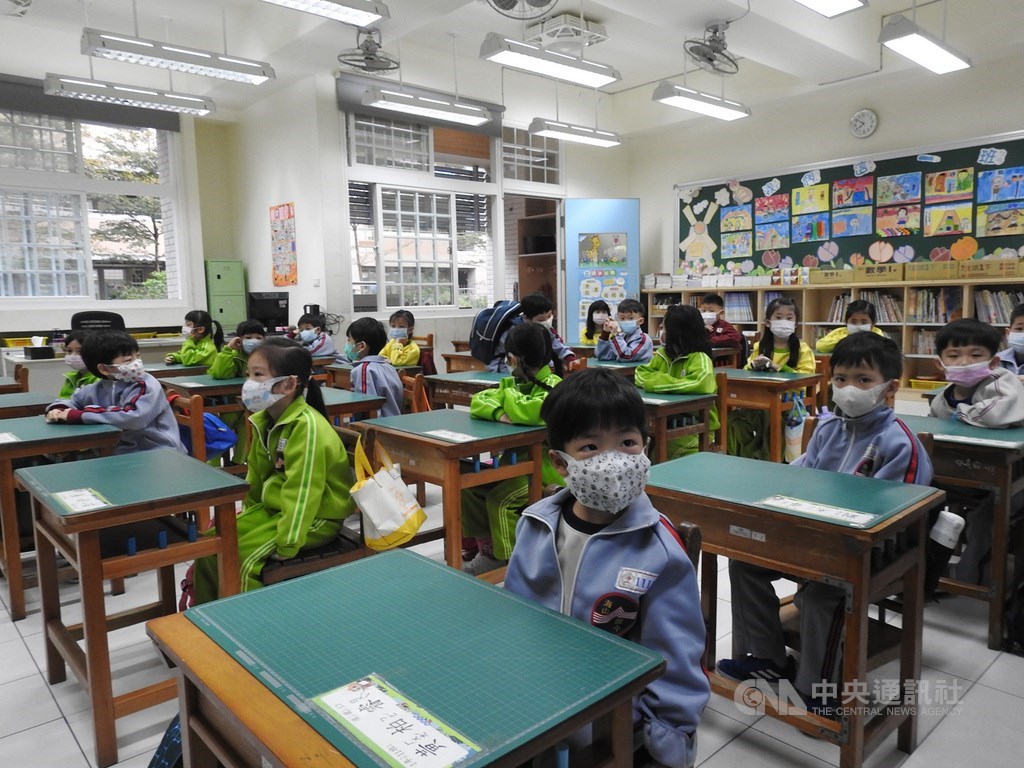 新北市高中以下各級學校25日開學,校方動員教職員及志工在門口為學生量體溫把關,教室內把桌椅拉開加大間隔,學童都戴口罩上課,在防疫中展開新學期。中央社記者王鴻國攝 109年2月25日