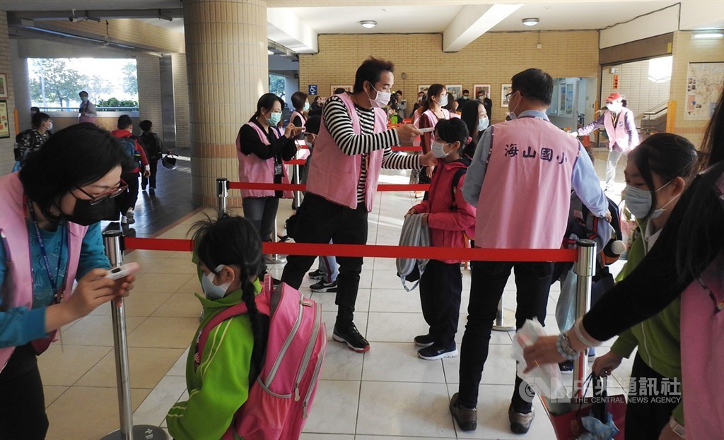 新北市高中以下各級學校25日開學,學生依序在校門口量完體溫才能進入校園。中央社記者王鴻國攝 109年2月25日
