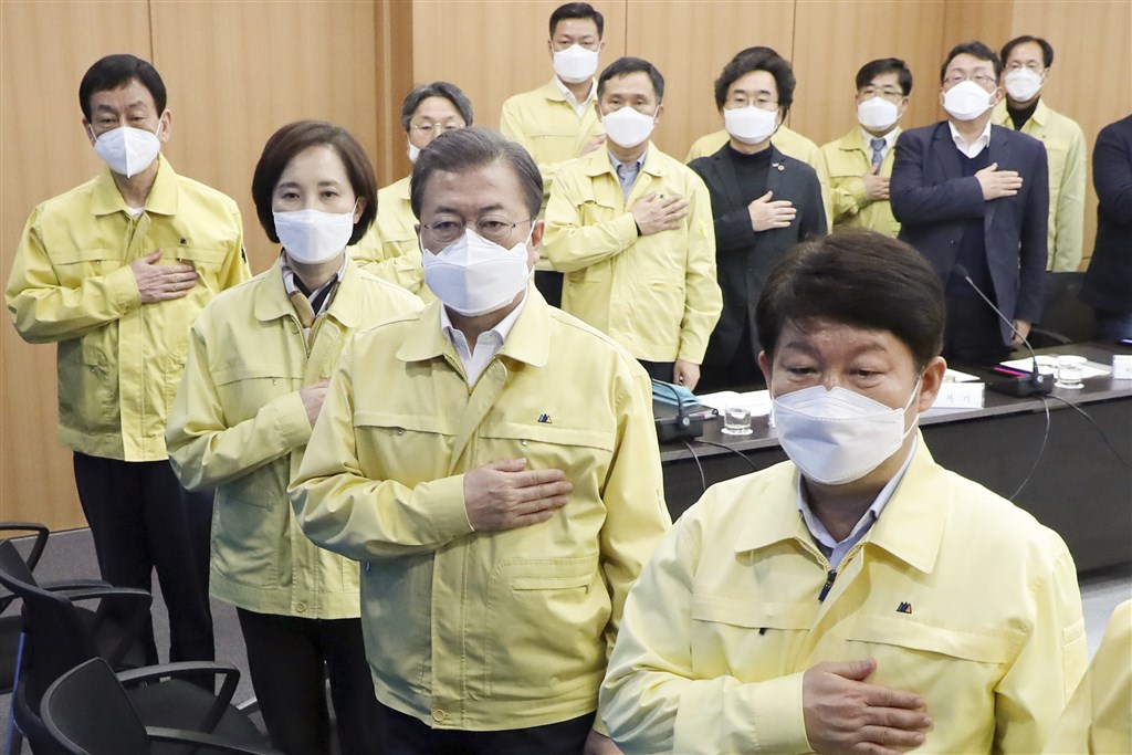 韓國總統文在寅(右2)25日與大邱市政府官員開會,由於大邱市經濟副市長李承鎬被指為武漢肺炎感染者,因此引起恐慌。李承鎬後經檢查判定為陰性,讓青瓦台虛驚一場。圖為文在寅與大邱市府官員開會升旗時致敬。(韓聯社提供)