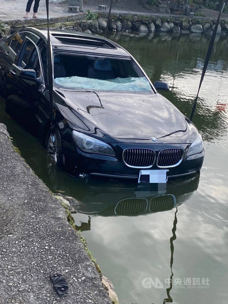 新北市淡水區小坪頂一處釣魚池27日有價值逾新台幣500萬元的BMW 750轎車衝入滅頂,警方獲報到場處理,並協助聯絡拖吊車將車輛吊起。(翻攝畫面)中央社記者王鴻國傳真 109年2月27日