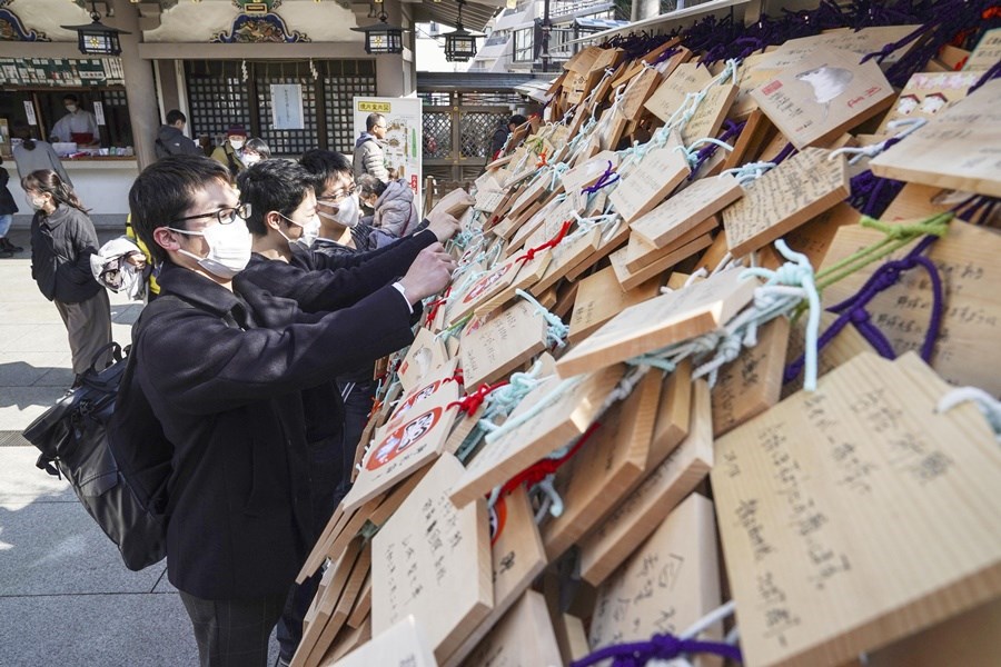 武漢肺炎蔓延全球,日本疫情漸成為外界關注焦點。圖為日本民眾參拜神社時戴口罩。(共同社提供)