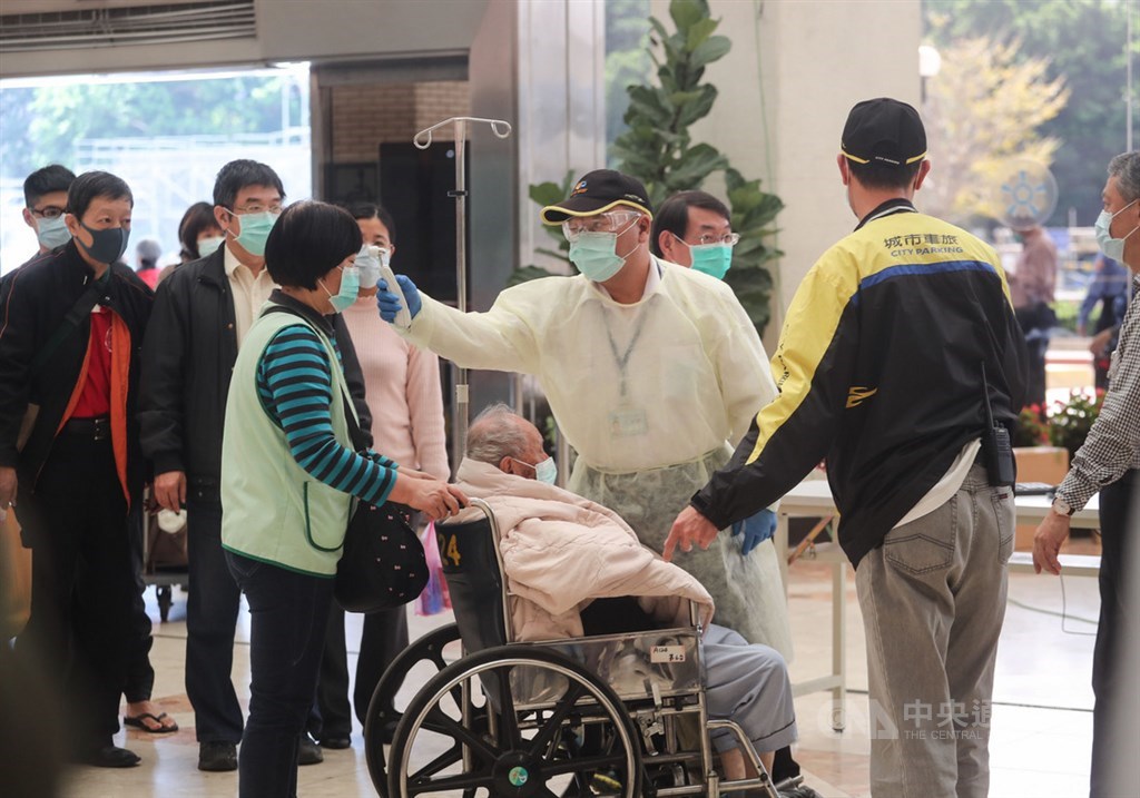 因應武漢肺炎疫情,台北榮民總醫院嚴格執行入院體溫測量,在入口處設置紅外線體溫感測儀,工作人員攔下體溫稍高的民眾,以額溫槍進行二次檢測。中央社記者裴禛攝 109年2月29日