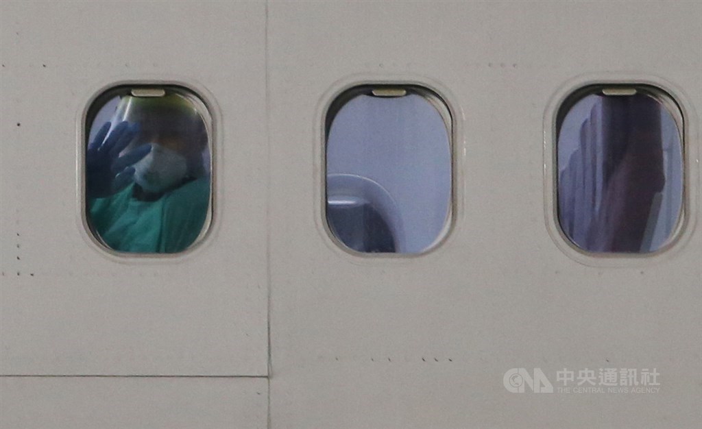 台灣派出包機接回日本郵輪鑽石公主號上台籍旅客及先遣醫師,2月21日晚間順利返台,機內穿著隔離衣的旅客透過機窗向外揮手致意。中央社記者邱俊欽桃園機場攝 109年2月21日