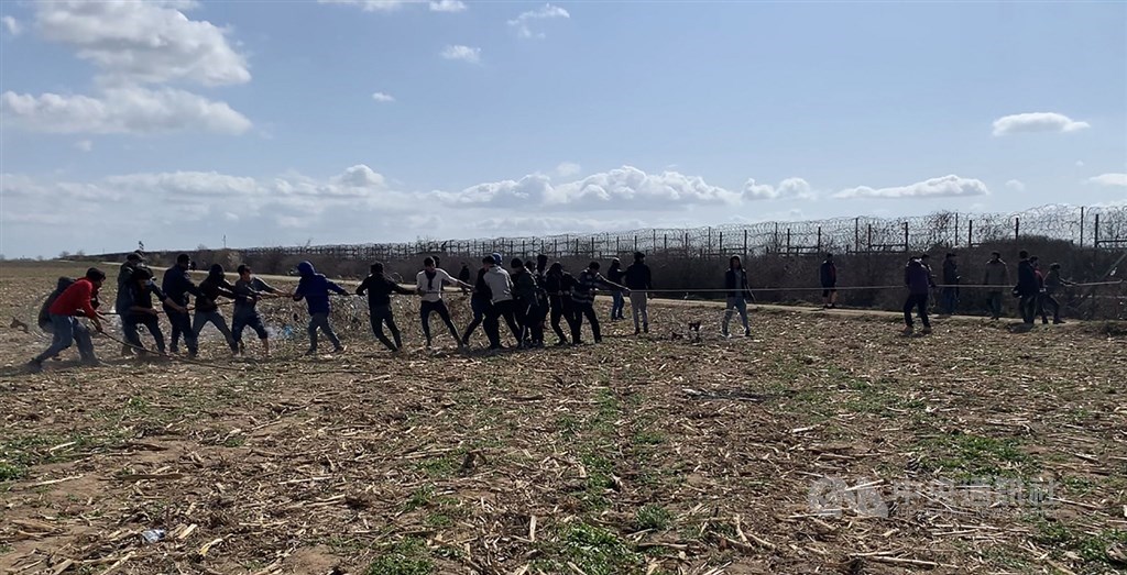 土耳其開放邊界,數以千計難民抵希臘邊境帕札庫勒邊界關卡,等待機會跨境入歐洲。一群難民7日以類似拔河方式,試圖將邊界圍籬上的金屬刺網圍籬抽出。中央社記者何宏儒帕札庫勒攝 109年3月10日