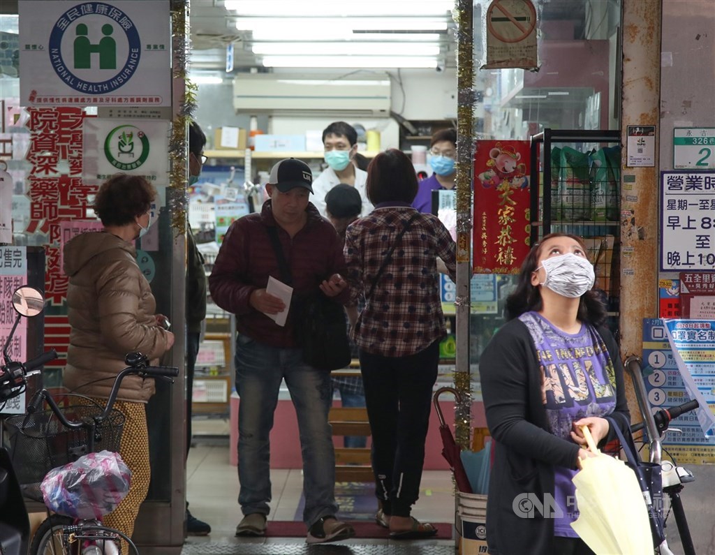 中央流行疫情指揮中心19日宣布,口罩實名制2.0預購第二輪將在25日開始,預購後4月2日領取。圖為民眾在藥局外排隊買口罩。(中央社檔案照片)