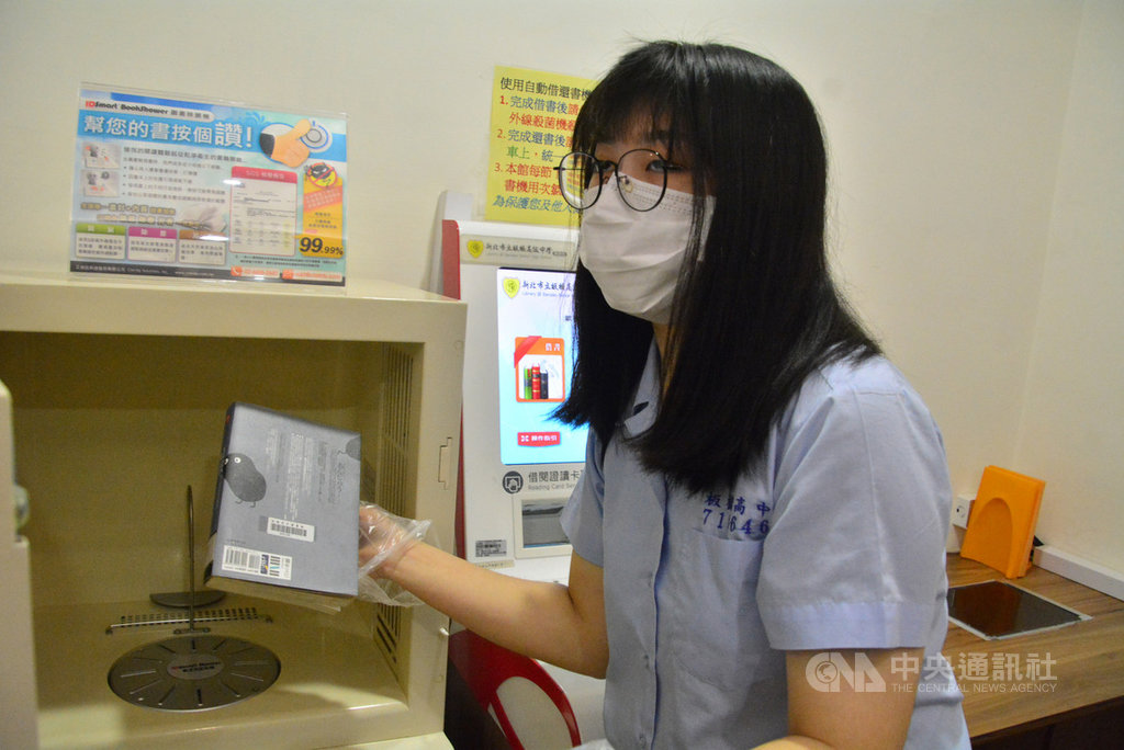 新北市教育局20日晚間核定,要求高中職以下學校自即日起,教職員工與學生進入校園內皆須配戴口罩。圖為109年2月24日板橋高中學生戴著口罩,示範圖書館書籍消毒流程。中央社記者黃旭昇新北市攝 109年3月20日