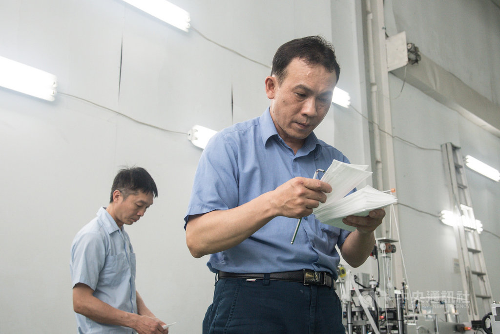 因應台灣民眾口罩需求,口罩國家隊加緊趕工打造口罩機台產線;長宏機械最後一條口罩機台產線在20日中午交機,工作人員逐一檢查口罩,確認生產品質。中央社記者林俊耀攝 109年3月20日