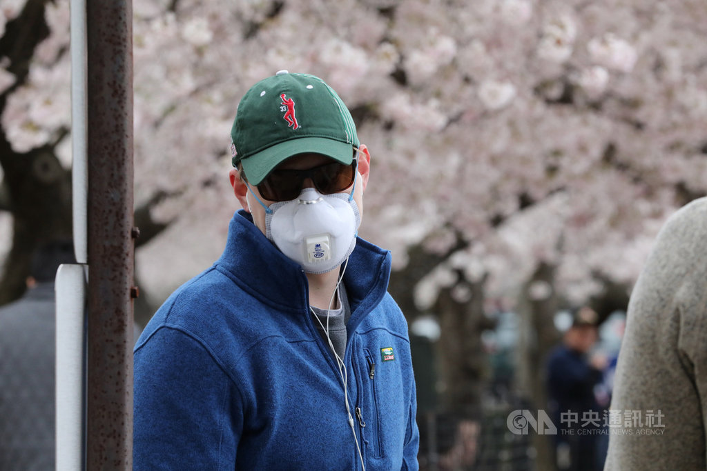 美國首府華盛頓櫻花21日達到盛開期,有人配戴口罩賞櫻,以避免感染2019年冠狀病毒疾病(COVID-19)。中央社記者徐薇婷華盛頓攝 109年3月22日