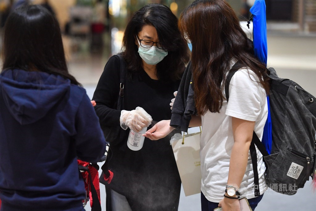 圖為桃園機場入境大廳,家長迎接孩子返台幫忙消毒。中央社記者林俊耀攝 109年3月22日