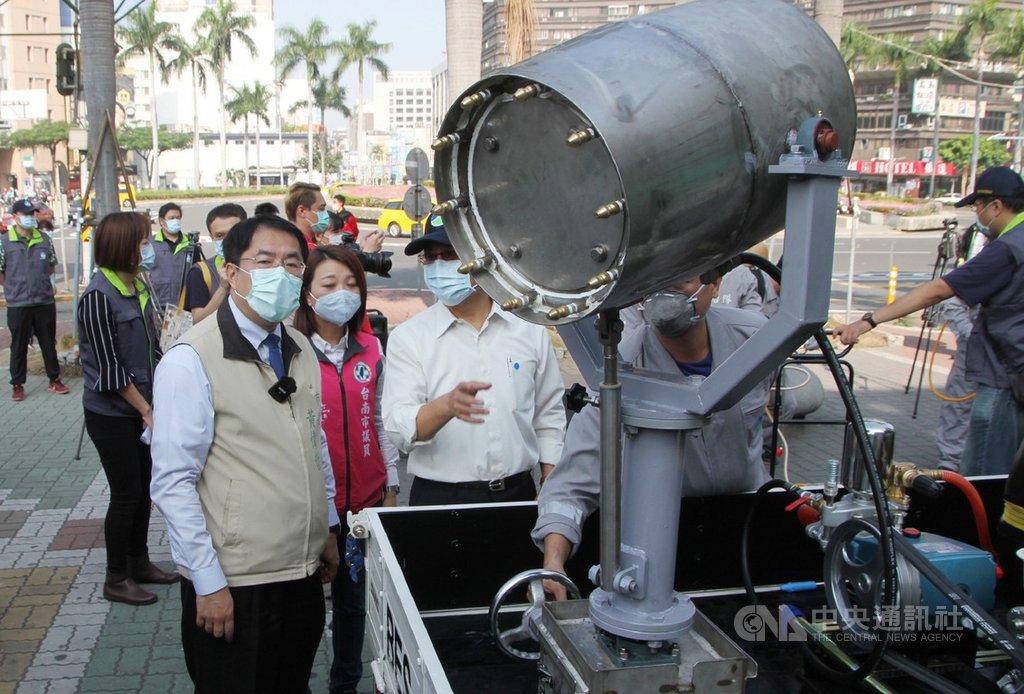 台南市政府26日針對車站等交通場站附近戶外空間加強消毒,市長黃偉哲(前左)前往視察,仔細了解環保局自行設計的砲霧台消毒車。中央社記者楊思瑞攝 109年3月26日