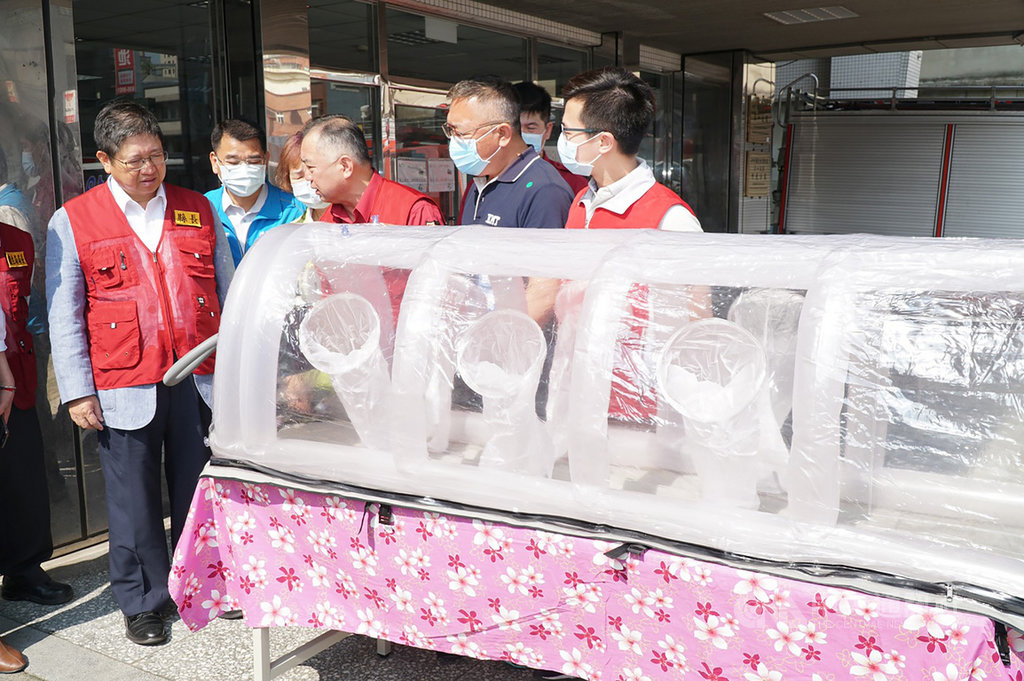 新竹縣消防局26日舉辦「居家檢疫及隔離病患出勤載送整備示範案」,消防員現場穿著全套式個人防護裝備,出動負壓隔離艙,並示範防疫送醫流程,縣長楊文科(前左)、局長孫福佑(前右3)也到場視察。中央社記者郭宣彣攝 109年3月26日